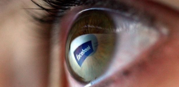 Logotipo do Facebook refletido no olho de uma mulher; rede social mudou e-mail padrão de perfis