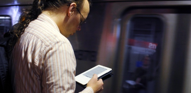 Homem l livro em seu aparelho Kindle, enquanto espera o metr nos Estados Unidos