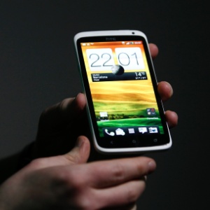 Homem segura o smartphone HTC One X; segundo empresa, ele é capaz de gravar vídeos e tirar fotos ao mesmo tempo - Gustau Nacarino/Reuters